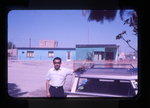 man beside a house and automobile by Haven L. Miller