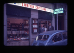 two men and one woman standing beside an automobile on a city street, Libreria Cristiana by Haven L. Miller